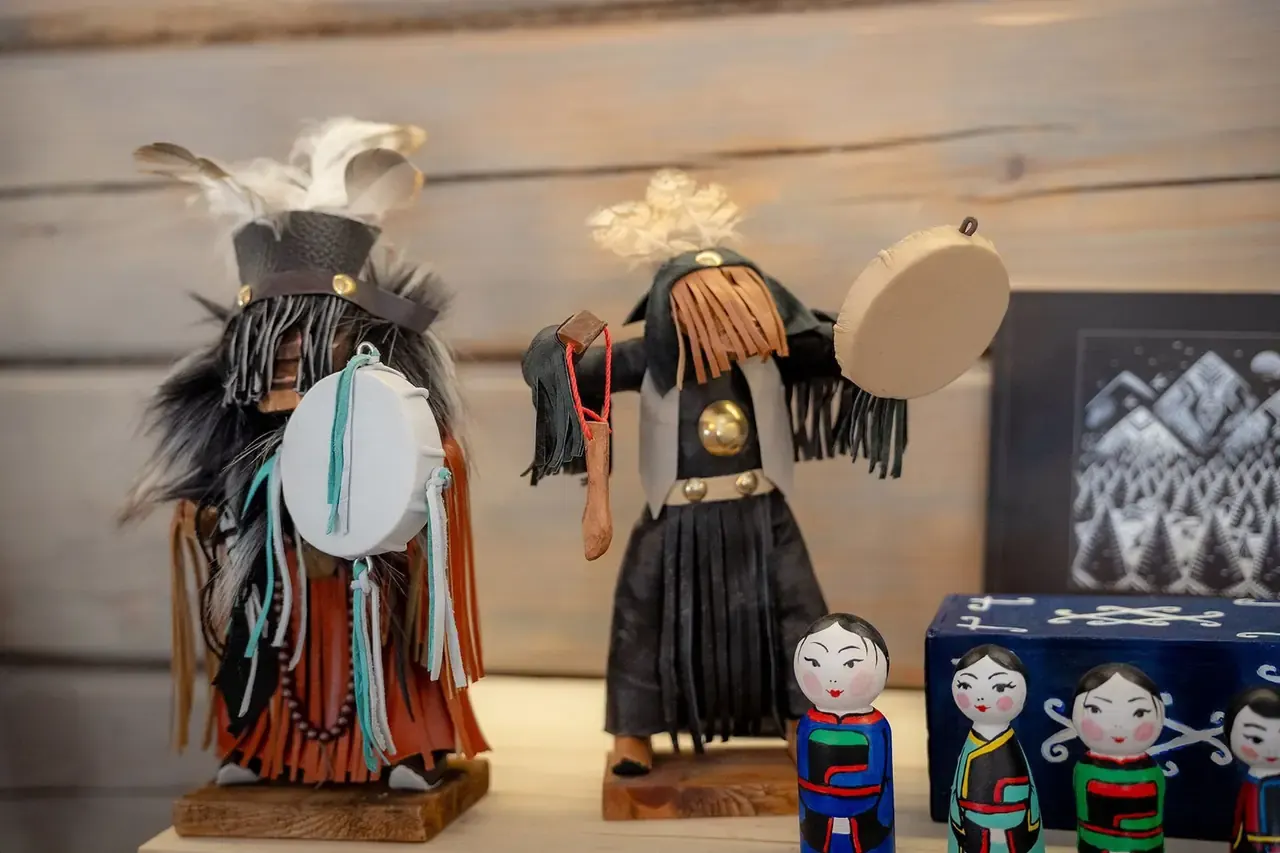 Hai tượng nhỏ mô phỏng trang phục shaman với trống da, mũ lông vũ, bên cạnh búp bê gỗ Buryat